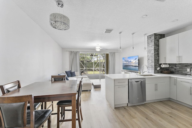 kitchen with light wood finished floors, dishwasher, decorative backsplash, a peninsula, and a sink