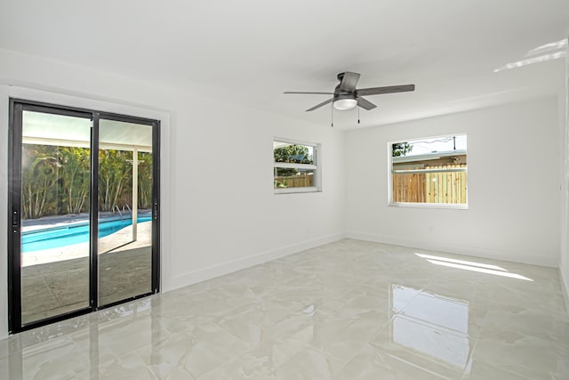 spare room with baseboards, marble finish floor, and a ceiling fan