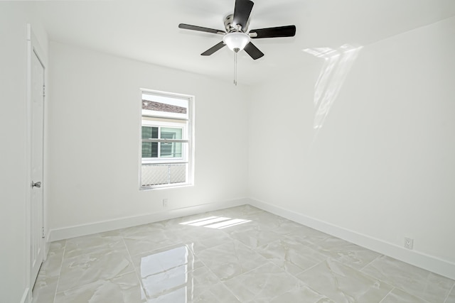 unfurnished room featuring a ceiling fan, baseboards, and marble finish floor