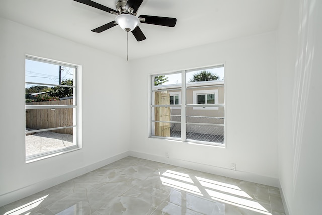 unfurnished room featuring a ceiling fan, baseboards, and marble finish floor