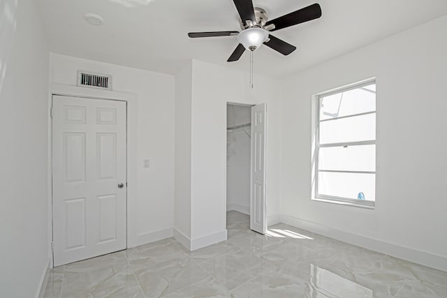 unfurnished bedroom featuring a ceiling fan, baseboards, visible vents, a closet, and a walk in closet