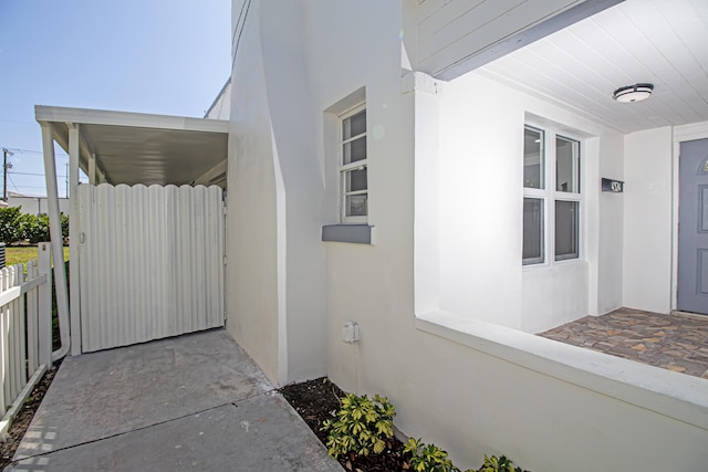 entrance to property featuring fence and stucco siding