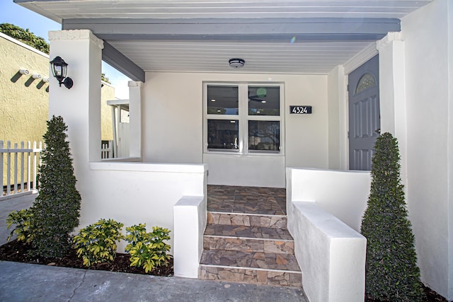 entrance to property featuring stucco siding and covered porch