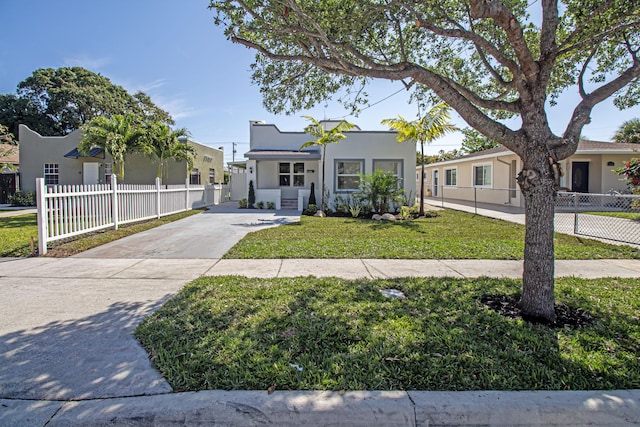 view of front of home featuring a fenced front yard, stucco siding, driveway, and a front yard