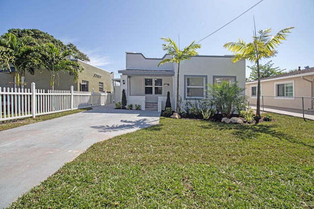 mediterranean / spanish house featuring stucco siding, concrete driveway, a front yard, and fence