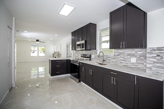 kitchen with a peninsula, a sink, ceiling fan, light countertops, and stainless steel appliances