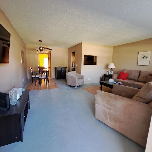 living area with a textured ceiling, concrete flooring, and a ceiling fan