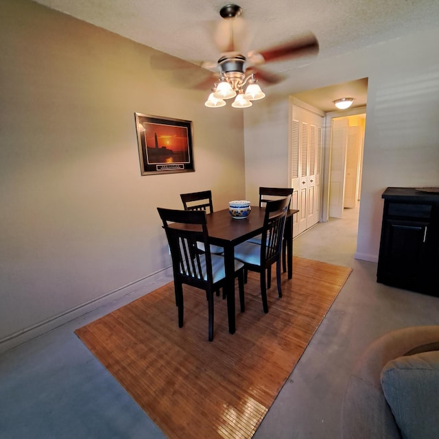 dining area with a ceiling fan, baseboards, and concrete floors