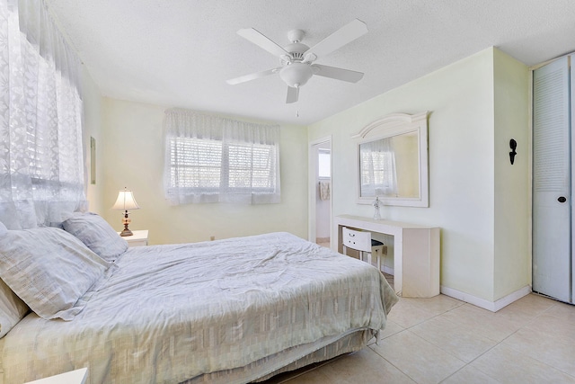 tiled bedroom featuring ceiling fan, baseboards, and a textured ceiling