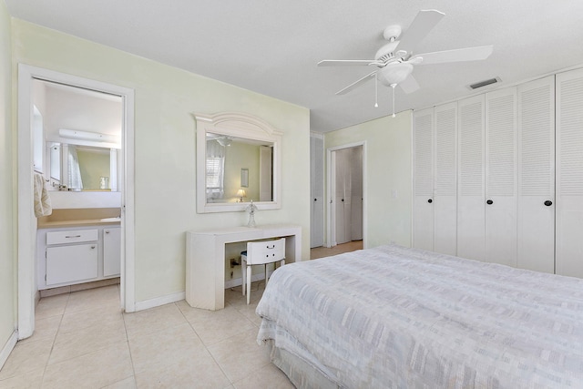 bedroom with visible vents, ensuite bath, light tile patterned floors, baseboards, and ceiling fan