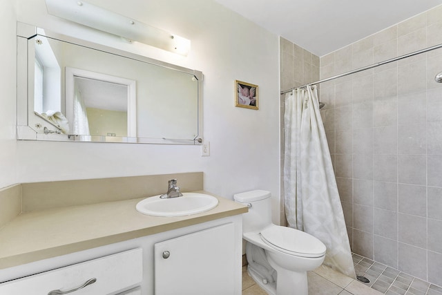 bathroom with tile patterned flooring, tiled shower, toilet, and vanity