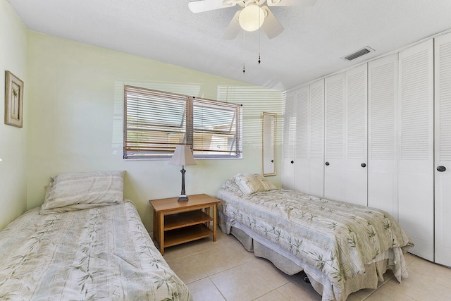 bedroom with visible vents, ceiling fan, lofted ceiling, light tile patterned floors, and a textured ceiling