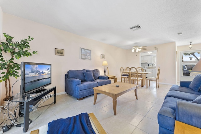 living area featuring visible vents, baseboards, light tile patterned flooring, a textured ceiling, and a ceiling fan