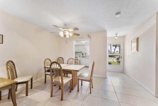 dining room with light tile patterned floors, baseboards, a textured ceiling, and ceiling fan