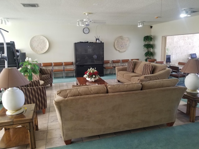 living area with visible vents, a textured ceiling, and light tile patterned flooring