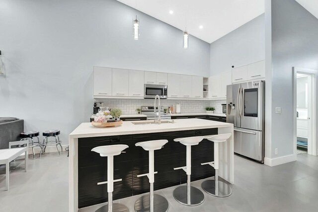 9238 E Vineland Ct E Unit E, Boca Raton, FL 33496 - kitchen featuring a breakfast bar, light countertops, appliances with stainless steel finishes, a towering ceiling, and a sink