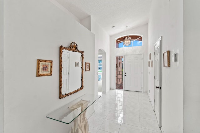 7267 Modena Dr, Boynton Beach, FL 33437 - entryway with a notable chandelier, a textured ceiling, arched walkways, light tile patterned flooring, and a towering ceiling