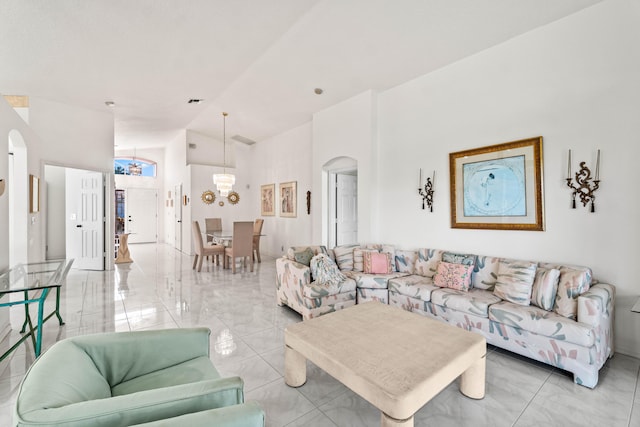 7267 Modena Dr, Boynton Beach, FL 33437 - living area with arched walkways, a notable chandelier, marble finish floor, and high vaulted ceiling