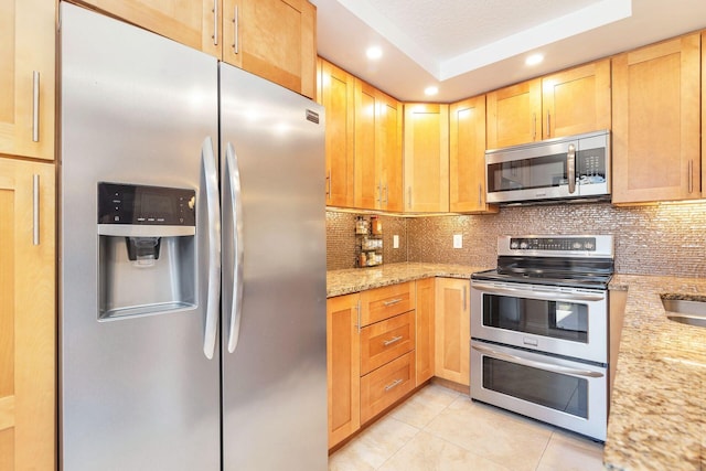 kitchen featuring light stone counters, light tile patterned flooring, recessed lighting, decorative backsplash, and appliances with stainless steel finishes