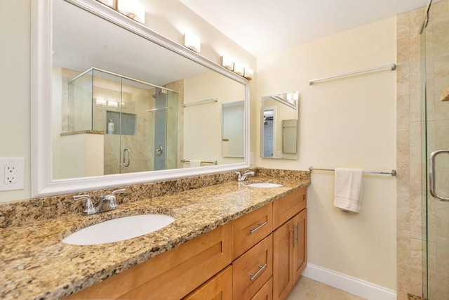 full bath with a sink, baseboards, double vanity, and a shower stall