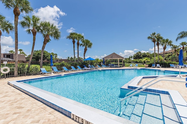 pool with a gazebo, fence, and a patio area