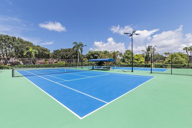 view of tennis court with community basketball court and fence