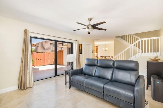 living room with stairway, baseboards, and ceiling fan with notable chandelier