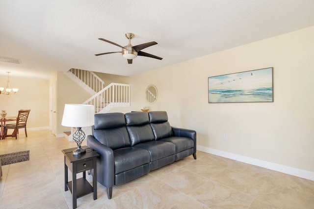 living room with baseboards, stairs, light tile patterned floors, ceiling fan with notable chandelier, and a textured ceiling