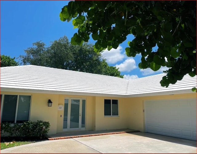 ranch-style home with concrete driveway, an attached garage, and stucco siding