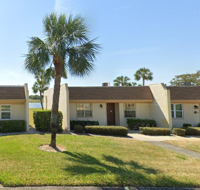 view of front facade with a shingled roof, a front lawn, and stucco siding