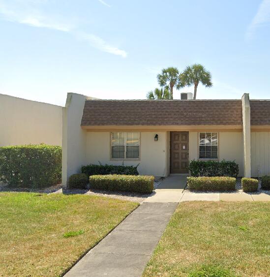 view of front of house featuring a front lawn, stucco siding, and a shingled roof