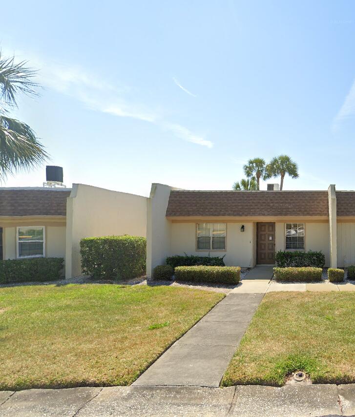 view of front facade featuring stucco siding, a front lawn, and roof with shingles