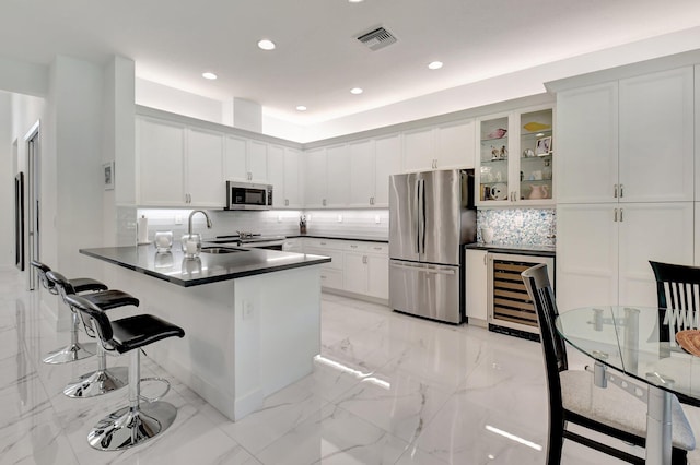 7855 Wildflower Shores Dr, Delray Beach, FL 33446 - kitchen with visible vents, a peninsula, appliances with stainless steel finishes, dark countertops, and marble finish floor