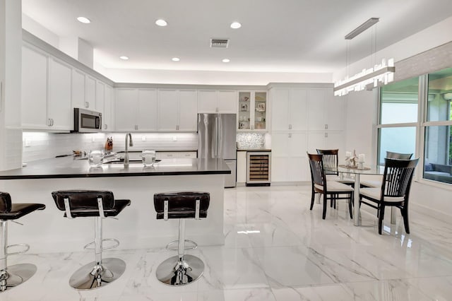 7855 Wildflower Shores Dr, Delray Beach, FL 33446 - kitchen with visible vents, wine cooler, a peninsula, marble finish floor, and stainless steel appliances