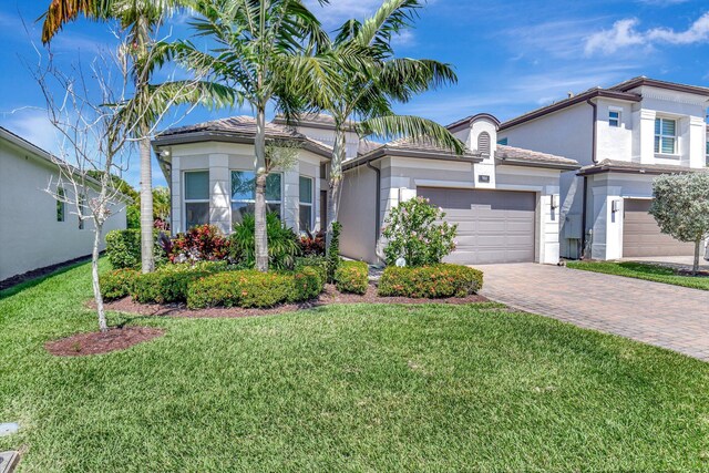 7855 Wildflower Shores Dr, Delray Beach, FL 33446 - view of front of property featuring stucco siding, a front lawn, a tile roof, decorative driveway, and an attached garage