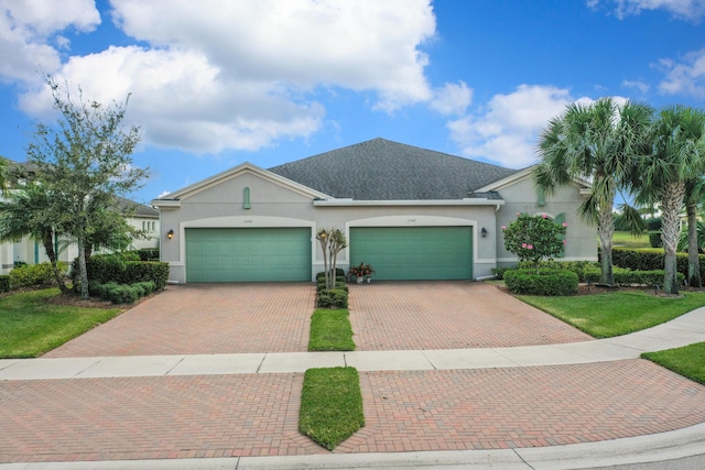 ranch-style house featuring stucco siding, a front yard, decorative driveway, and a garage