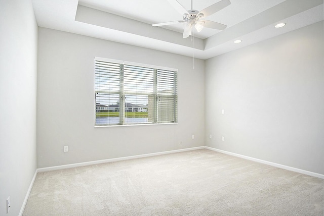 carpeted spare room with recessed lighting, ceiling fan, baseboards, and a tray ceiling