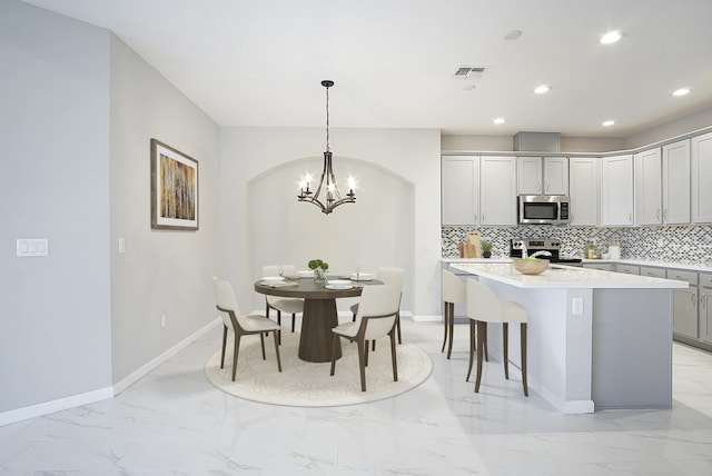 11243 SW Parkside Dr, Port Saint Lucie, FL 34987 - kitchen featuring marble finish floor, appliances with stainless steel finishes, light countertops, decorative backsplash, and a chandelier