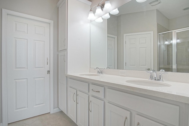 bathroom featuring a sink, a stall shower, double vanity, and tile patterned flooring