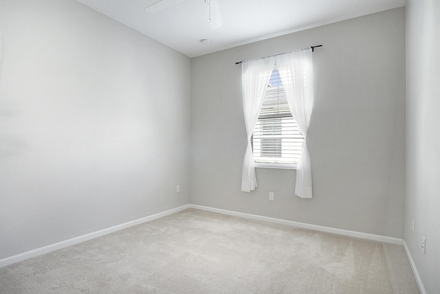 spare room with baseboards, light carpet, and ceiling fan