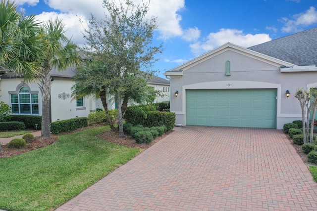 ranch-style home with stucco siding, an attached garage, decorative driveway, and a front lawn