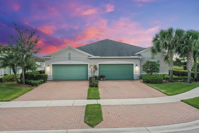 view of front of home with a front yard, decorative driveway, an attached garage, and stucco siding