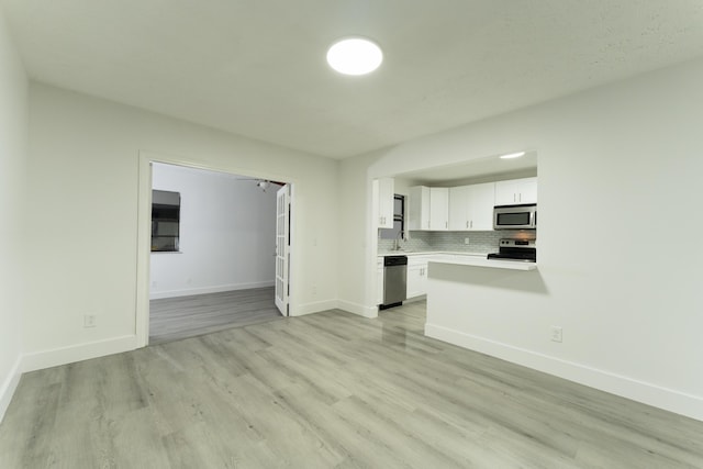 unfurnished living room with baseboards, light wood finished floors, and a sink