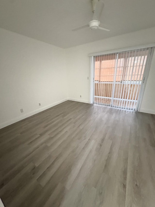 spare room featuring baseboards, ceiling fan, and dark wood finished floors