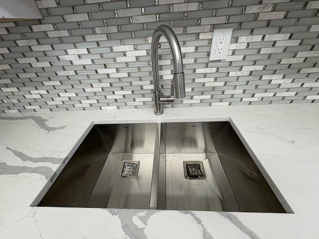 room details featuring gray cabinetry, backsplash, light stone counters, and a sink