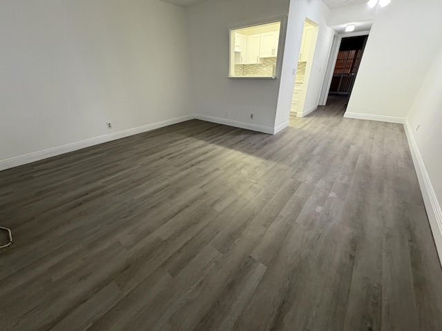 spare room featuring baseboards and dark wood finished floors