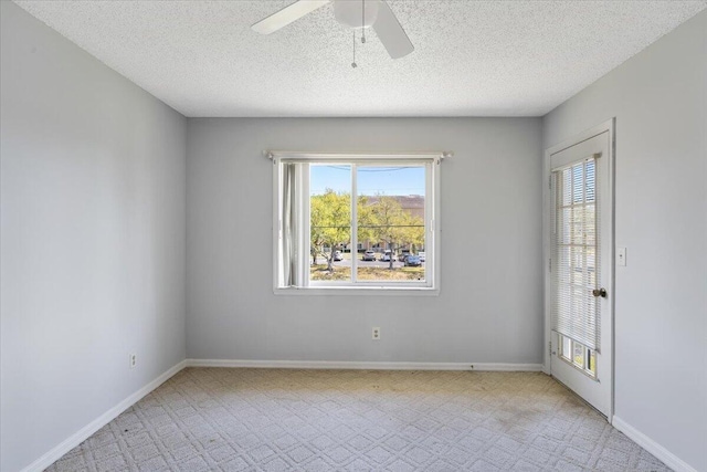 spare room featuring a textured ceiling, baseboards, and a ceiling fan