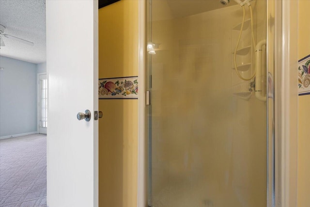 bathroom with a shower stall, a ceiling fan, baseboards, and a textured ceiling