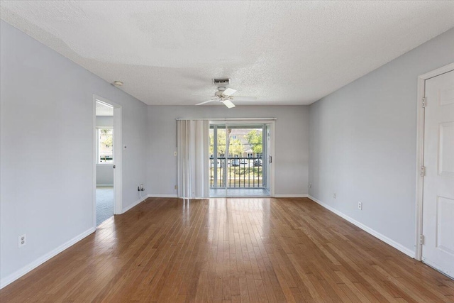 unfurnished room with hardwood / wood-style floors, a ceiling fan, baseboards, and a textured ceiling