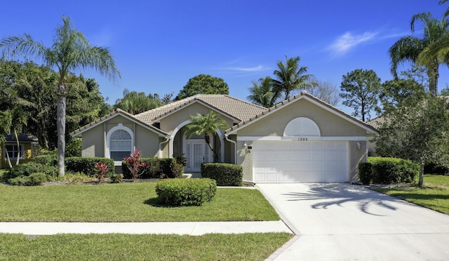 ranch-style home featuring a front yard, stucco siding, concrete driveway, a garage, and a tile roof